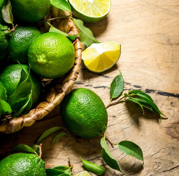 fresh-limes-with-leaves-basket-wooden-table